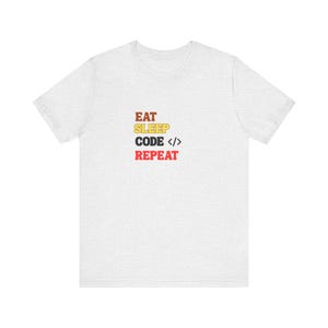 Könnte beinhalten: Hellgraues T-Shirt mit dem Aufdruck "EAT SLEEP CODE < /> REPEAT" in Braun, Gelb, Rot und Schwarz. Das T-Shirt hat einen Rundhalsausschnitt und ist aus weichem Stoff.