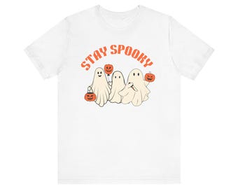 May include: White t-shirt with the text "Stay Spooky" in orange letters. Three white ghosts are holding jack-o'-lanterns and a balloon.
