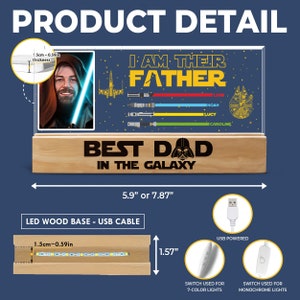 K&ouml;nnte beinhalten: Ein Holzsockel mit einer durchsichtigen Acrylplatte mit einem Star Wars-Motiv. Die Platte hat einen Bilderrahmen mit einem Bild eines Mannes mit Bart. Der Text "Ich bin ihr Vater" ist in Gelb und Schwarz geschrieben. Der Text "Bester Papa der Galaxie" ist in Schwarz geschrieben. Der Sockel hat ein USB-Kabel und einen Schalter f&uuml;r 7-Farben-Lichter und einen Schalter f&uuml;r monochromatische Lichter.