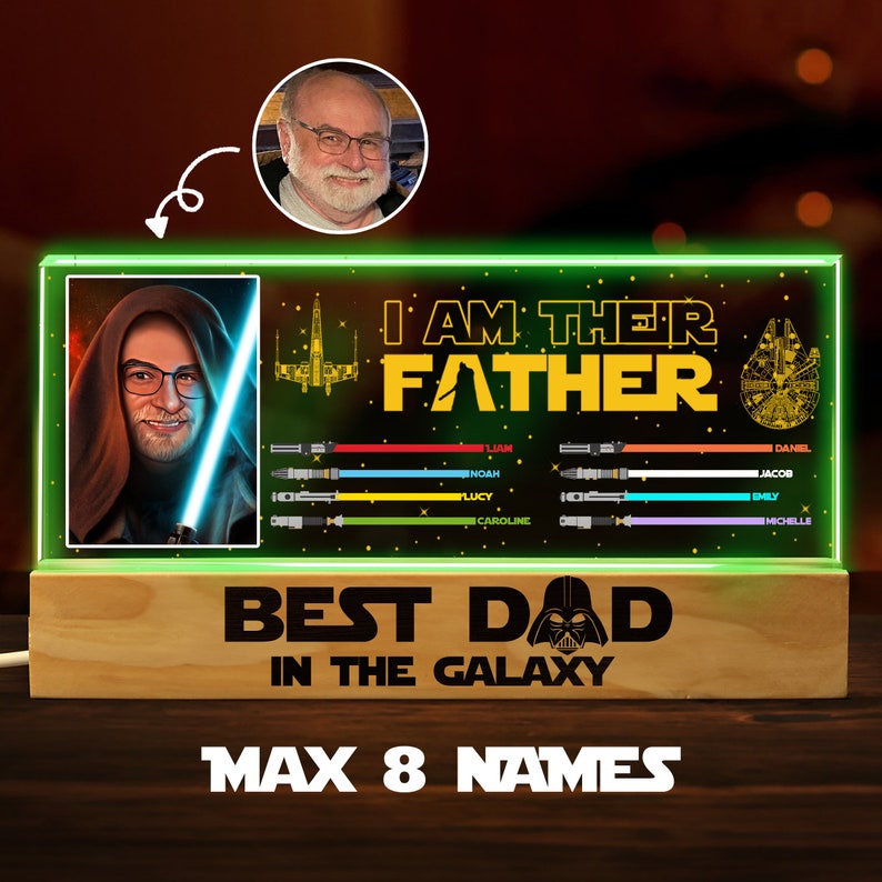 K&ouml;nnte beinhalten: Ein gr&uuml;n-schwarzes beleuchtetes Schild mit Star Wars-Thema. Das Schild zeigt ein Portr&auml;t eines Mannes in einem braunen Kapuzengewand, ein Lichtschwert, ein Raumschiff und den Text "Ich bin ihr Vater". Unter dem Portr&auml;t befinden sich acht Zeilen Text mit Namen, jede mit einer farbigen Lichtschwertgrafik. Das Schild zeigt auch den Text "Bester Papa der Galaxie" und eine Grafik von Darth Vader. Das Schild steht auf einem Holzsockel mit dem Text "Max 8 Namen".