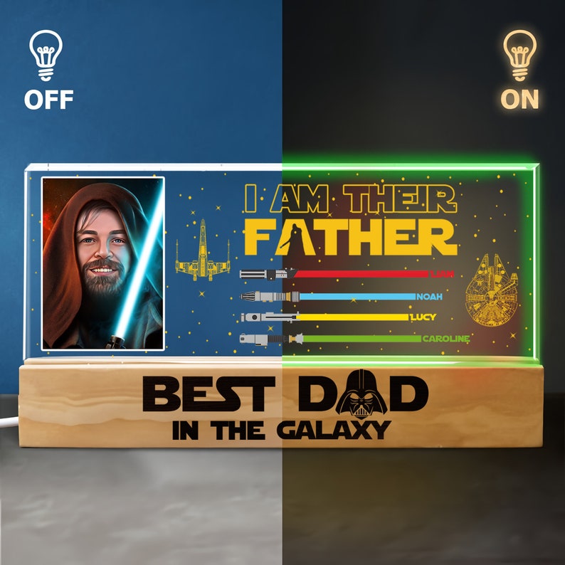 K&ouml;nnte beinhalten: Ein beleuchtetes Holzschild mit Star Wars-Motiv. Das Schild zeigt ein Bild eines Jedi-Ritters mit einem Lichtschwert, einem Raumschiff und dem Text "Ich bin ihr Vater". Unter dem Bild steht der Text "Bester Papa der Galaxie" mit einer Darth Vader-Grafik. Das Schild hat einen Lichtschalter an der Seite.