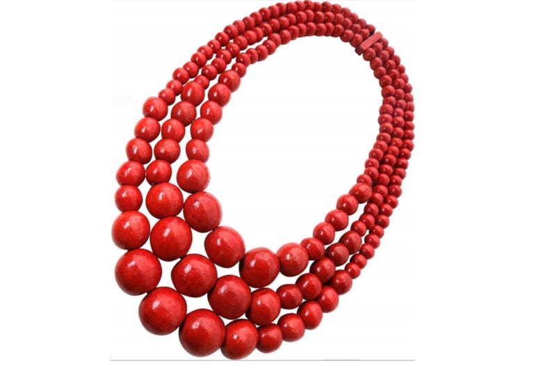 May include: A three-strand necklace featuring vibrant red beads. The necklace has varying bead sizes, with larger beads at the front and smaller ones towards the back. The beads are evenly spaced and strung together, creating a bold and eye-catching accessory.