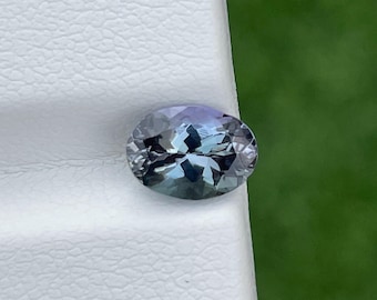May include: A light blue oval-shaped gemstone with a slight purple hue.