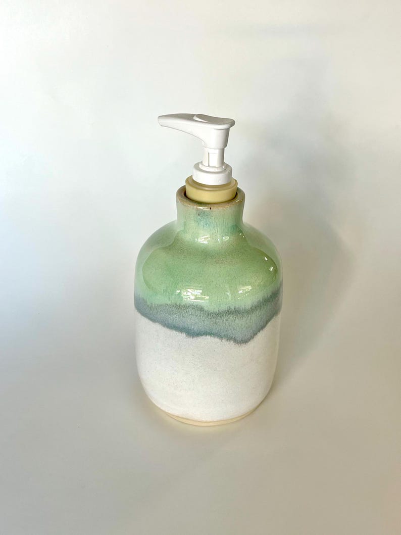 Pu&ograve; includere: Un dispenser di sapone in ceramica con corpo arrotondato e smalto bicolore. La met&agrave; superiore &egrave; di un tenue verde menta che sfuma in una base bianca testurizzata. Un meccanismo a pompa in plastica bianca &egrave; fissato sulla parte superiore.