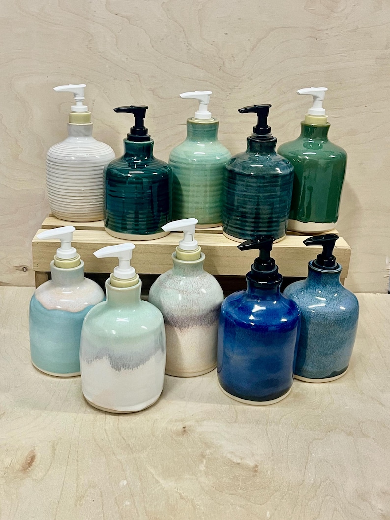 Pu&ograve; includere: Una collezione di dieci dispenser per sapone in ceramica in varie tonalit&agrave; di blu, verde e bianco. Ogni dispenser presenta un corpo arrotondato con una texture liscia o a coste e un meccanismo a pompa in plastica bianca o nera, su due livelli.