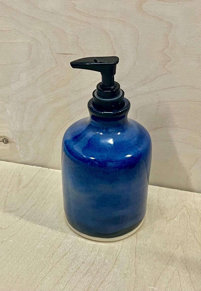 Pu&ograve; includere: Un dispenser di sapone cilindrico in ceramica caratterizzato da una profonda smaltatura blu cobalto lucida con sottili variazioni tonali. Il contenitore ha un corpo liscio e arrotondato ed &egrave; dotato di una pompa in plastica nera.