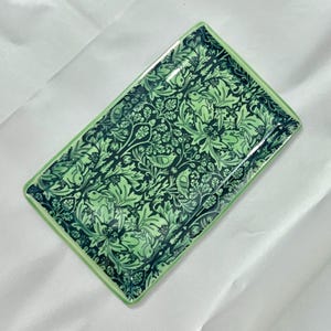 May include: A rectangular ceramic tray featuring a detailed botanical pattern in shades of dark forest green and light mint green. The design includes intricate illustrations of rabbits, small birds, oak leaves, and acorns across the surface.