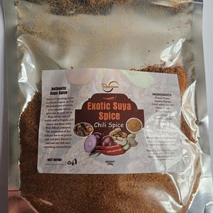 May include: A clear, resealable plastic pouch containing 200g of brown Exotic Suya Spice Chili Spice. The label features text describing the spice blend, ingredients including peanut powder, smoked paprika, and chilli, with illustrations of red onions, peanuts, and chilli peppers.