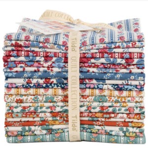 Peut inclure: Une pile de carrés de tissu pliés de la collection Tilda Quilt, attachés avec un ruban de marque. Le tissu présente divers motifs floraux et rayures dans des tons de rouge, bleu, jaune et vert sur fond blanc, avec une étiquette en papier.