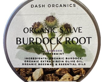 May include: A round, silver tin of Dash Organics Organic Salve Burdock Root. The label features text and an illustration of burdock flowers and leaves. Ingredients include organic burdock, olive oil, beeswax, and essential oils.
