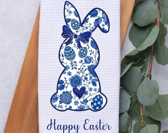 May include: White kitchen towel with a blue and white floral patterned Easter bunny with a blue bow and the text "Happy Easter".