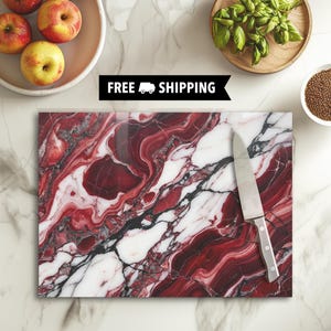 May include: A rectangular cutting board with a red, white, and black marble pattern. A stainless steel knife rests on the board. The image also includes a bowl of apples, a bowl of basil, and a bowl of seeds.