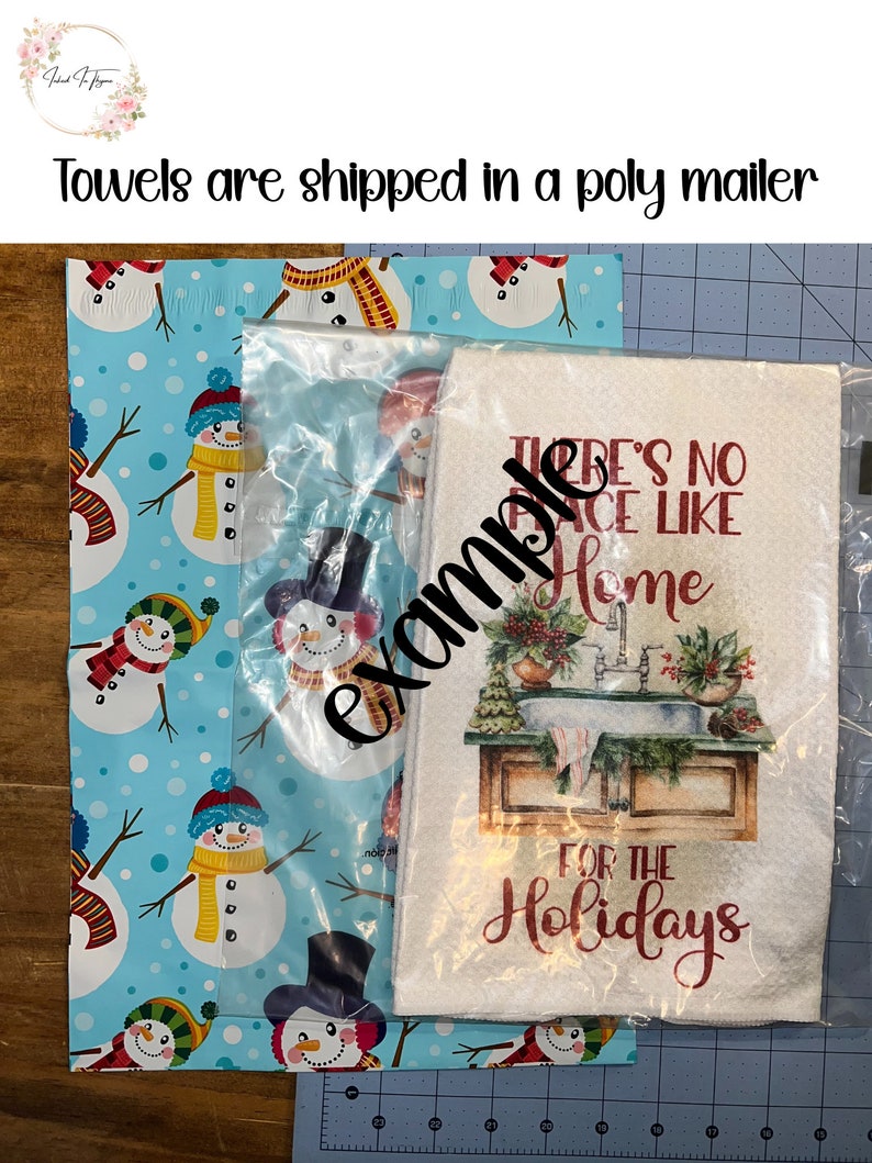 Pu&ograve; includere: Un asciugamano da cucina bianco con testo rosso che recita "There's No Place Like Home For The Holidays". L'asciugamano &egrave; avvolto in un sacchetto di plastica trasparente e posizionato su carta da regalo blu con un motivo a pupazzo di neve.