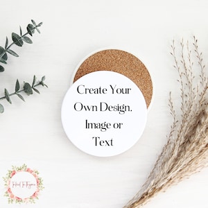 May include: A white ceramic coaster with a cork base, featuring the text "Create Your Own Design, Image or Text." The coaster is round and sits on a white surface, with decorative greenery and dried grass.
