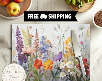 May include: A rectangular cutting board featuring a vibrant illustration of various wildflowers in shades of purple, orange, yellow, and white. A silver kitchen knife with a metallic blade and handle rests on the right side of the board.