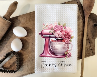 May include: White kitchen towel with a pink stand mixer with a bowl full of pink flowers and the text "Jennies Kitchen".