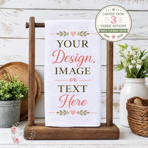 May include: A white waffle-weave kitchen towel hanging on a dark wooden stand. The towel features the text "YOUR Design, IMAGE or TEXT Here" in a mix of dark green and pink script and serif fonts, accented by small pink hearts and green leaf motifs.