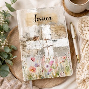 May include: A rectangular notebook with a personalized cover featuring the name Jessica in black script. The design includes a white cross overlaying a vintage-style background with handwritten text and a colorful watercolor floral border at the base.