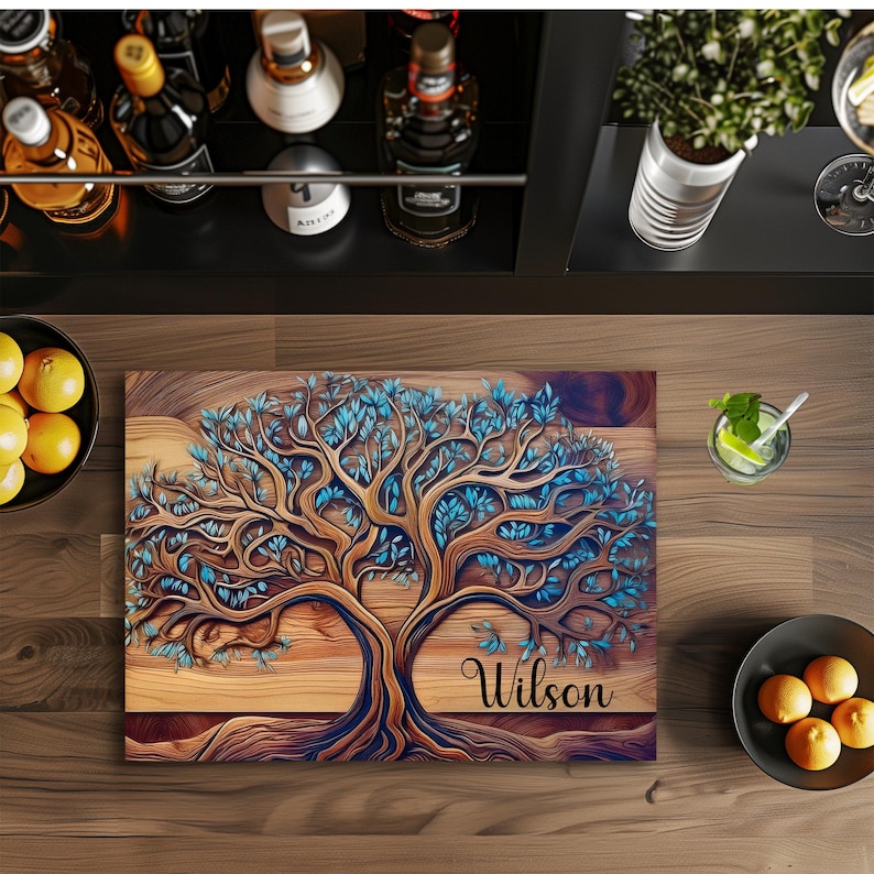 K&ouml;nnte beinhalten: Ein rechteckiges Holzschneidebrett mit einer detaillierten Abbildung eines Baumes mit braunen &Auml;sten und leuchtend blauen Bl&auml;ttern. Der Name Wilson ist in schwarzer Schreibschrift auf der unteren rechten Seite des Brettes aufgedruckt, das auf einer dunklen Oberfl&auml;che liegt.
