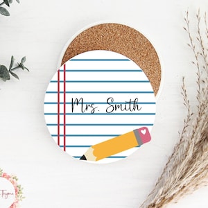 May include: A white ceramic coaster with a blue and red lined design, a yellow pencil with a pink eraser, and the text "Mrs. Smith".