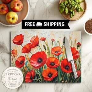 May include: A rectangular cutting board featuring a vibrant oil painting of red poppy flowers with dark centers and green stems. A silver metal kitchen knife with a riveted handle rests diagonally across the floral surface of the board.