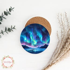 May include: A round ceramic coaster with a colorful aurora borealis scene. The coaster features a dark blue sky with vibrant green, purple, and pink lights. The scene is set against a dark mountain range and a reflective body of water.