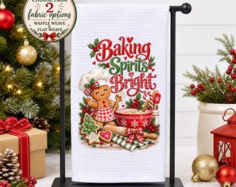 May include: A white waffle weave kitchen towel hanging on a black metal stand. The towel features a gingerbread person wearing a chef hat, a red mixing bowl, a rolling pin, and the text Baking Spirits Bright in red and green lettering.