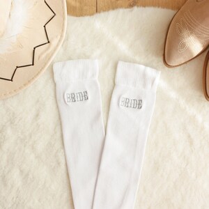 May include: A pair of white knee-high socks with the word "Bride" embroidered on each sock.