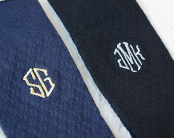 May include: Two pairs of dark blue socks with embroidered initials. One pair has the initials "SG" in gold thread and the other pair has the initials "JMK" in white thread.