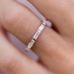 Op de afbeelding: Een delicate gouden ring met een rij baguette-geslepen diamanten.