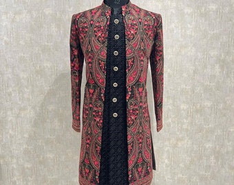 Puede incluir: Una chaqueta larga de manga larga negra y roja con estampado paisley. La chaqueta tiene un cuello mandarín y cierre de botones y está adornada con lentejuelas.