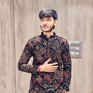 May include: A black long-sleeved shirt with a colourful geometric pattern. The shirt has a mandarin collar and a button closure.