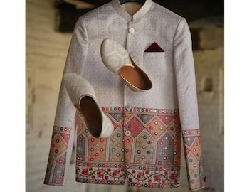 May include: A white embroidered jacket with a colourful patterned border and a red pocket square. Two white embroidered shoes are floating in the air.