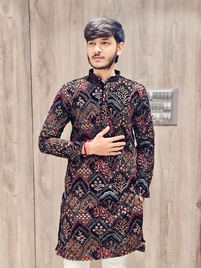 May include: A black long-sleeved shirt with a colourful geometric pattern. The shirt has a mandarin collar and a button closure.