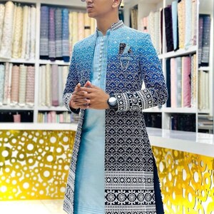 May include: A long, blue and white patterned jacket with a mandarin collar and a light blue shirt underneath. The jacket has a gradient design with a darker blue at the bottom and a lighter blue at the top. The shirt has a button-up front and a white collar.