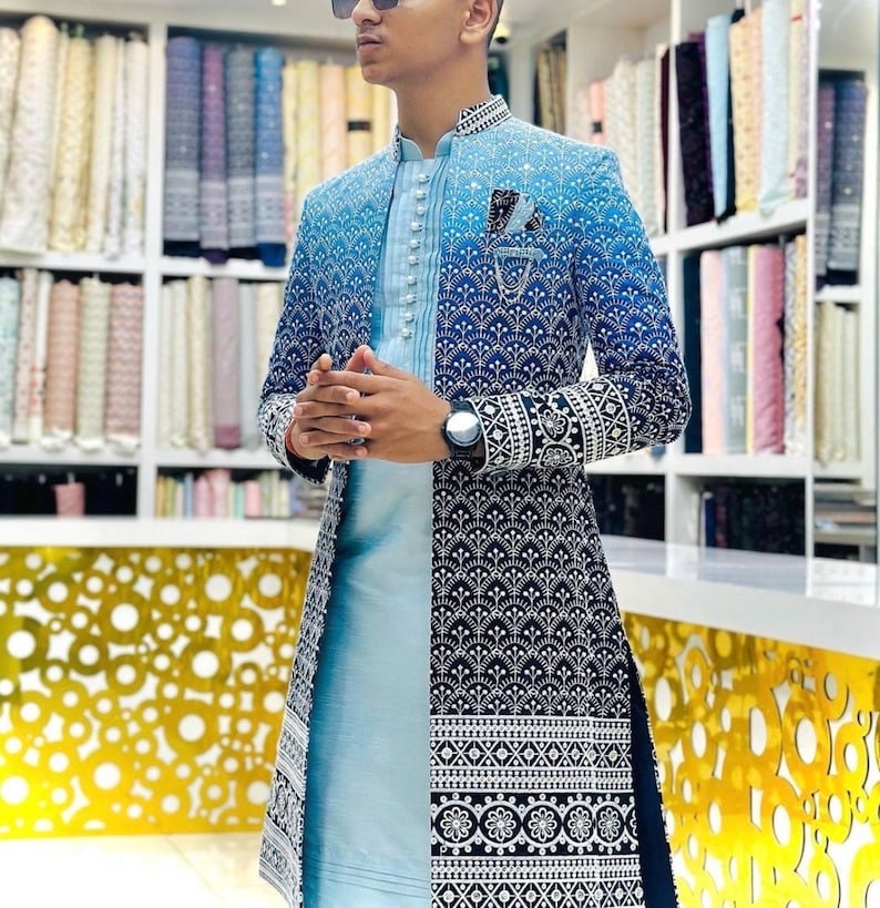 May include: A long, blue and white patterned jacket with a mandarin collar and a light blue shirt underneath. The jacket has a gradient design with a darker blue at the bottom and a lighter blue at the top. The shirt has a button-up front and a white collar.
