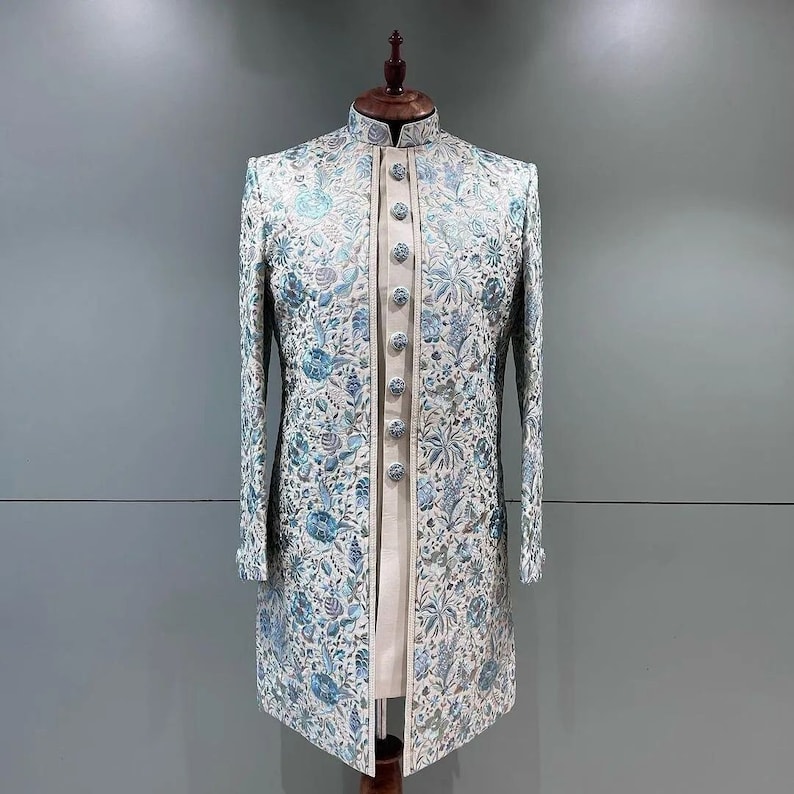 May include: A white long-sleeved jacket with a blue floral pattern. The jacket has a mandarin collar and a button closure.