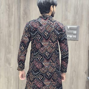 May include: A black long-sleeved kurta with a geometric pattern in shades of red, gold, and white. The kurta is made of velvet and has a high neckline.