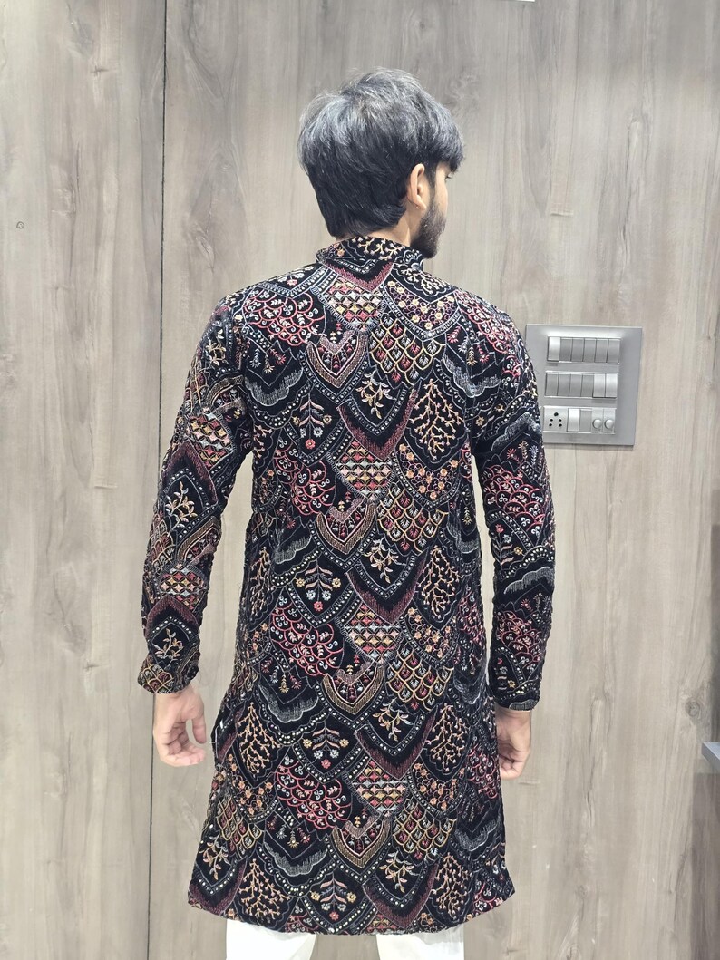 May include: A black long-sleeved kurta with a geometric pattern in shades of red, gold, and white. The kurta is made of velvet and has a high neckline.