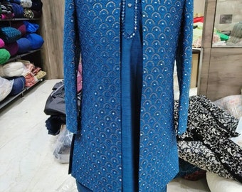 Op de afbeelding: Een blauwe kurta en bijpassend jasje met ingewikkelde borduursels en versieringen. Het jasje heeft een staande kraag en een knoopsluiting. De kurta heeft een lange, vloeiende vorm.