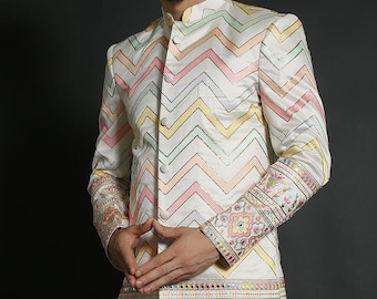 May include: A white long-sleeved jacket with a chevron pattern in pink, yellow, and green. The jacket has a mandarin collar and a button closure. The cuffs and hem are decorated with floral embroidery.