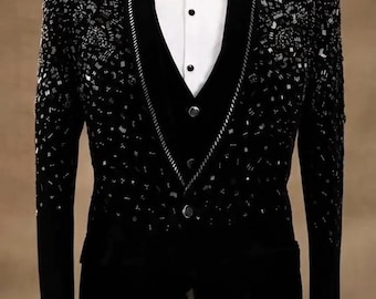 May include: A black blazer featuring dense, shimmering beadwork on the shoulders and chest, paired with a black velvet vest, a crisp white button-down shirt, and a matching black bow tie, displayed on a mannequin torso.