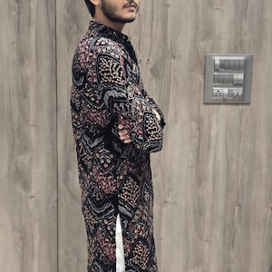 May include: A black long-sleeved shirt with a colourful floral pattern. The shirt has a mandarin collar and a button closure. The shirt is made of a soft, comfortable fabric.