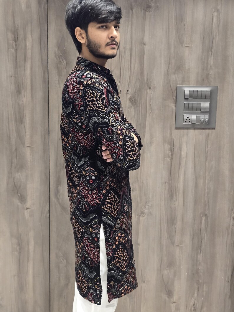 May include: A black long-sleeved shirt with a colourful floral pattern. The shirt has a mandarin collar and a button closure. The shirt is made of a soft, comfortable fabric.