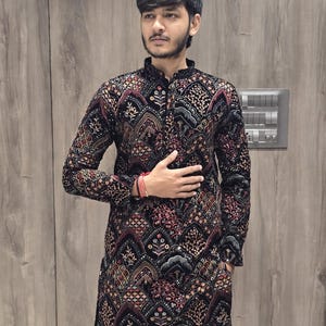 May include: A black long-sleeved kurta with a red, gold, and silver patterned design. The kurta has a mandarin collar and a button closure.