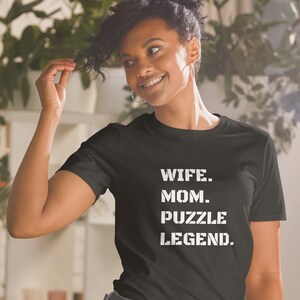 May include: A black t-shirt with white text that reads "Wife. Mom. Puzzle Legend."