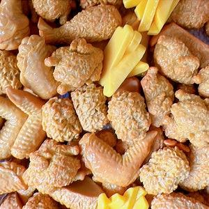 Peut inclure: Vue aérienne de divers aliments frits, notamment des ailes de poulet, des nuggets et des frites. Les morceaux de poulet sont brun doré et les frites sont jaune vif. Les aliments sont disposés de près, remplissant le cadre.