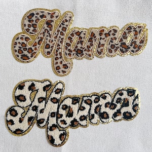 May include: Two "Mama" patches. The word "Mama" is written in a cursive font, with a leopard print pattern in brown and black. The patches are outlined with gold glitter.