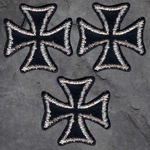 May include: Three black iron cross patches with silver stitching. The patches are on a gray background.