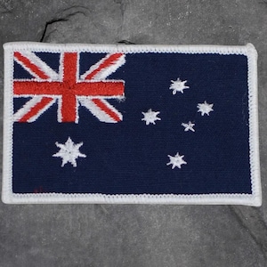 May include: A rectangular patch featuring the Australian flag. The flag has a dark blue background with the Union Jack in the upper left corner, a red St. George's Cross, and white stars representing the Southern Cross constellation.